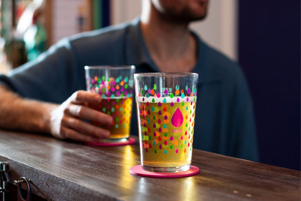 Two colorful glasses with polka dot Big Drop Alcohol-Free design on a bar counter